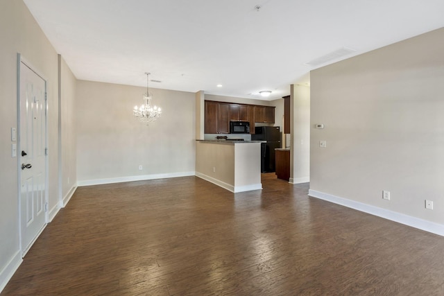 unfurnished living room with a notable chandelier, visible vents, dark wood-type flooring, and baseboards