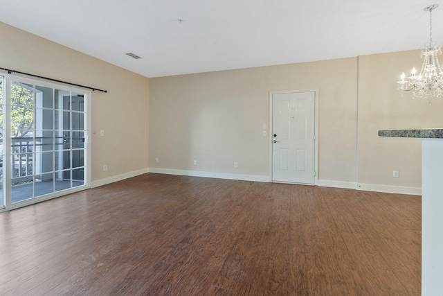 empty room with a chandelier, visible vents, dark wood finished floors, and baseboards