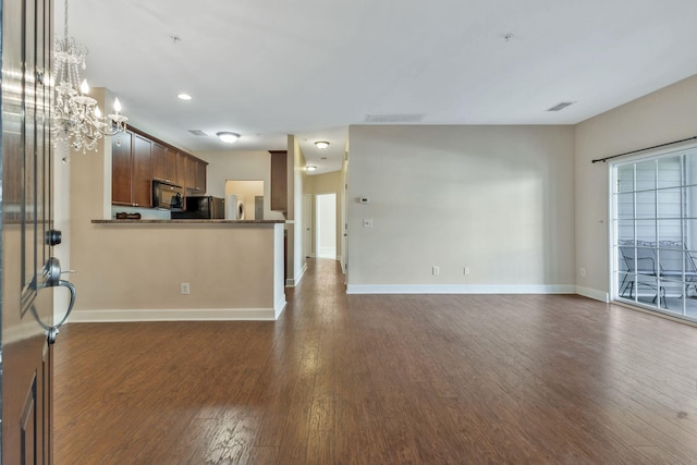 unfurnished living room with visible vents, baseboards, an inviting chandelier, and dark wood finished floors