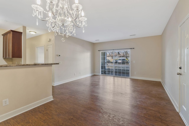 unfurnished living room featuring an inviting chandelier, dark wood-style floors, baseboards, and visible vents