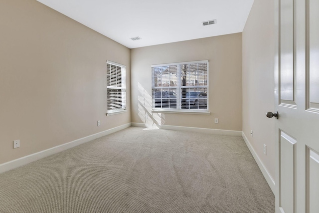 carpeted spare room with visible vents and baseboards