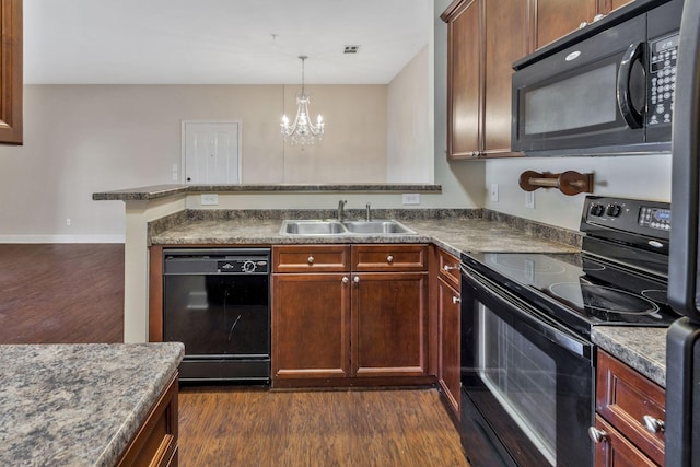 kitchen with a sink, a chandelier, a peninsula, black appliances, and dark wood-style flooring