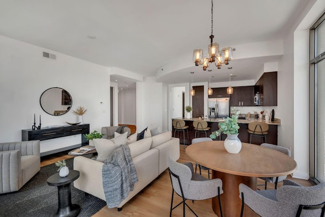 living area featuring a chandelier, visible vents, and light wood-style floors