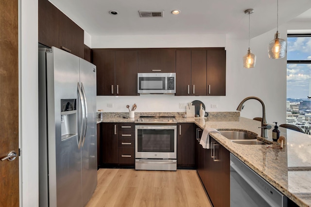 kitchen with visible vents, a sink, stainless steel appliances, dark brown cabinetry, and light wood finished floors