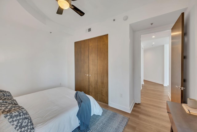 bedroom featuring visible vents, a ceiling fan, a closet, light wood-style floors, and baseboards