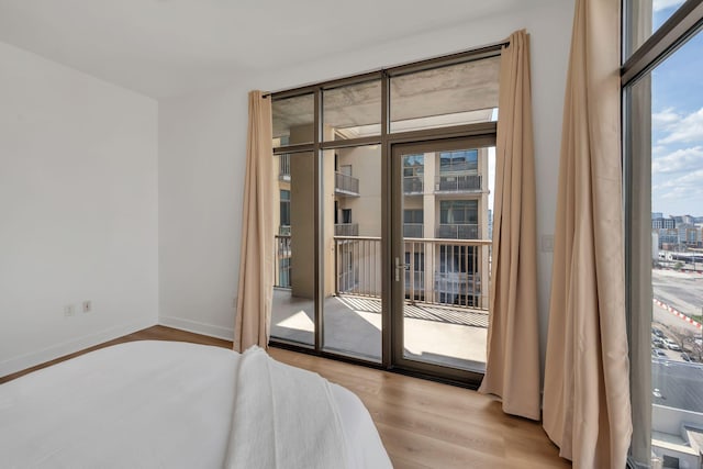 bedroom with access to exterior, wood finished floors, and baseboards