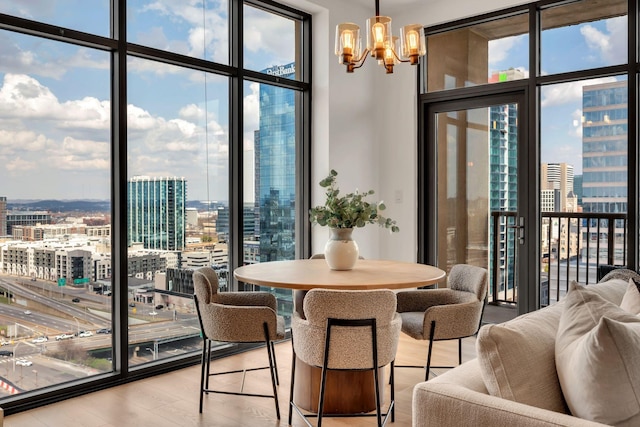 dining area featuring a notable chandelier, a city view, floor to ceiling windows, and light wood-type flooring