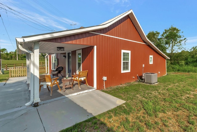 rear view of property featuring central air condition unit, a yard, and fence