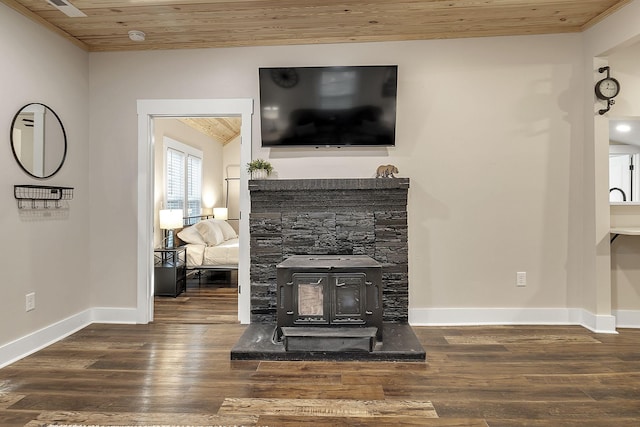 living area with baseboards, wood finished floors, wooden ceiling, and a wood stove