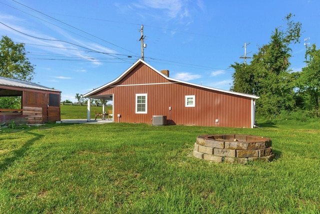 exterior space with an outbuilding, a lawn, an outdoor fire pit, cooling unit, and a chimney