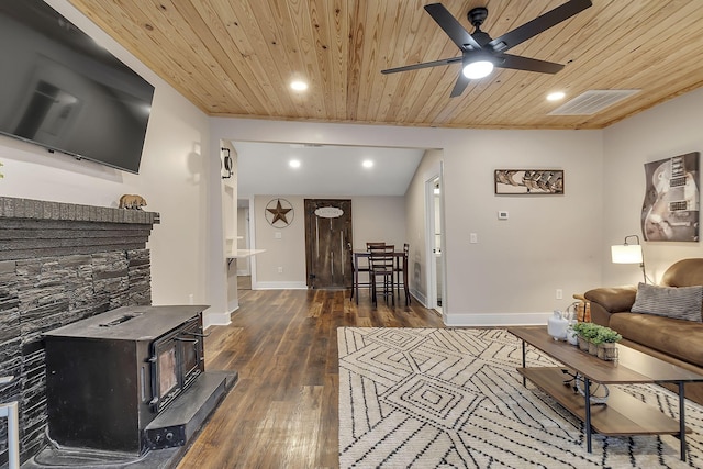 living area with visible vents, ceiling fan, wooden ceiling, a wood stove, and hardwood / wood-style flooring