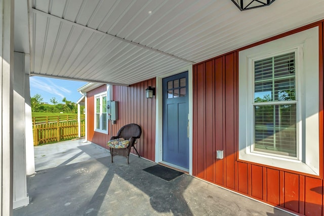 view of exterior entry featuring board and batten siding and fence