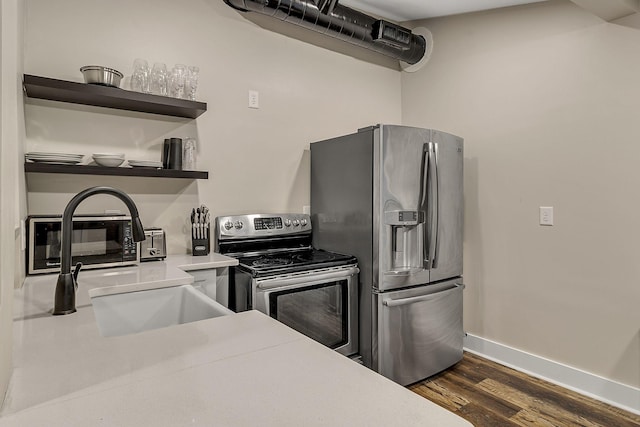 kitchen featuring open shelves, dark wood-style floors, appliances with stainless steel finishes, light countertops, and baseboards