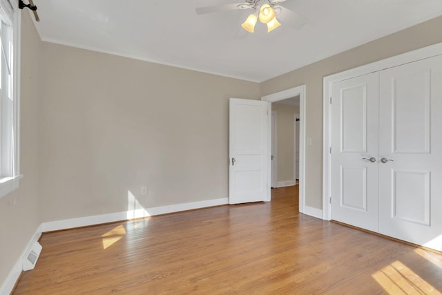 unfurnished bedroom featuring wood finished floors, visible vents, a closet, and baseboards