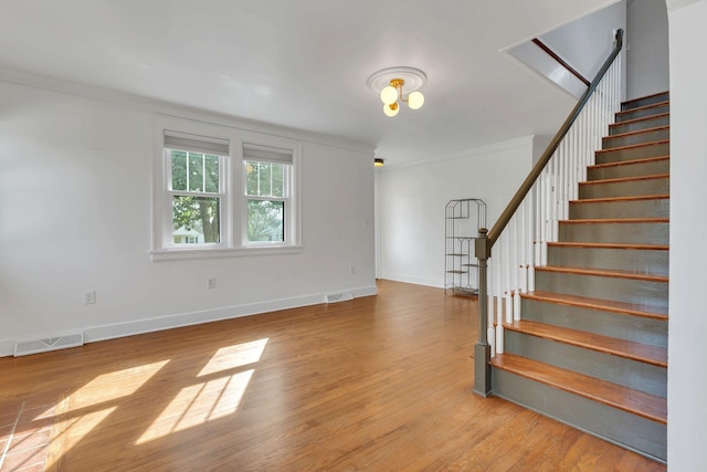 interior space with visible vents, baseboards, wood finished floors, and crown molding