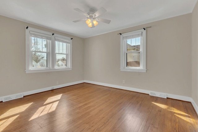 spare room featuring crown molding, baseboards, visible vents, and wood-type flooring