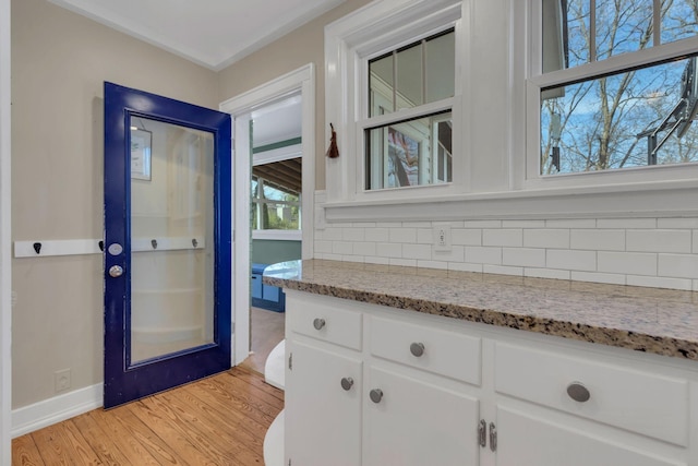 bathroom featuring backsplash, vanity, baseboards, and wood finished floors