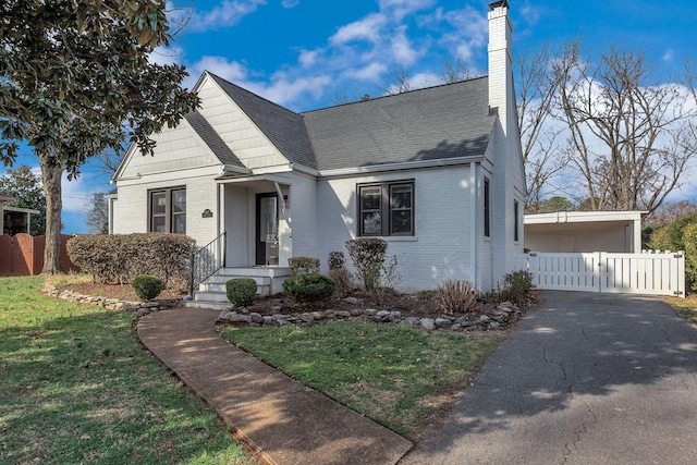 bungalow with a front lawn, fence, brick siding, and a chimney