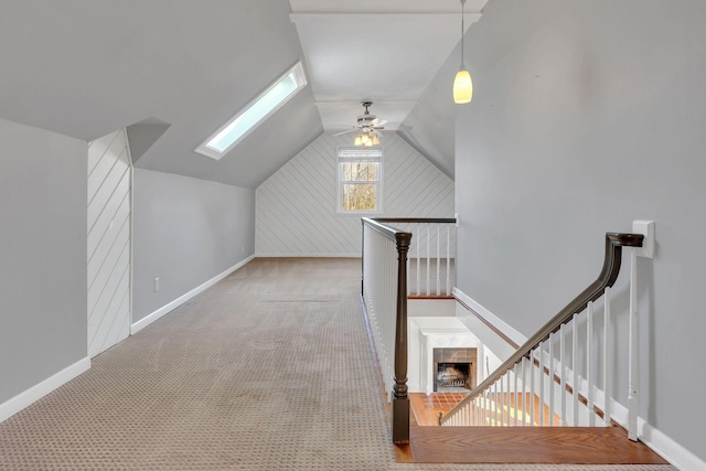 additional living space featuring lofted ceiling with skylight, baseboards, a ceiling fan, and carpet floors