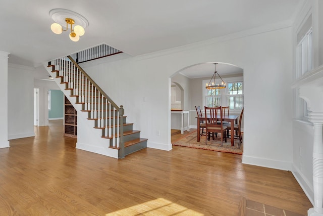 interior space featuring wood finished floors, arched walkways, a chandelier, and baseboards