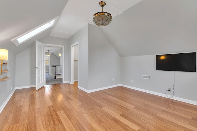 bonus room with visible vents, vaulted ceiling with skylight, light wood-type flooring, and baseboards