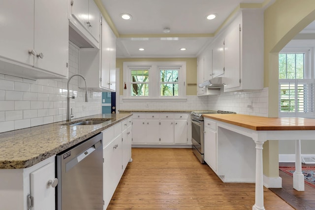 kitchen featuring a sink, under cabinet range hood, white cabinetry, appliances with stainless steel finishes, and light wood finished floors