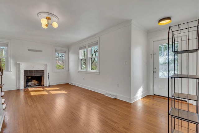 unfurnished living room featuring wood finished floors, visible vents, and a healthy amount of sunlight