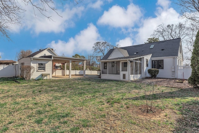 rear view of house with a carport, a yard, fence, and a sunroom