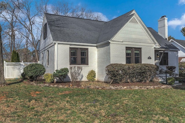 view of front of property with a front yard, fence, and brick siding