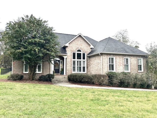 view of front of house with a front lawn, brick siding, and a shingled roof