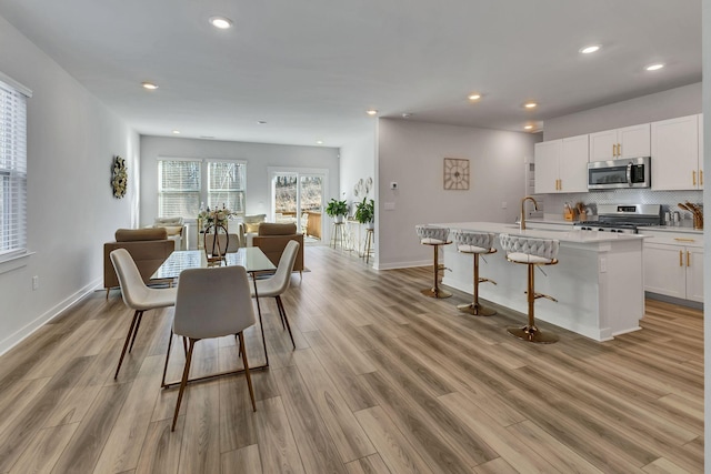 dining room featuring light wood finished floors, recessed lighting, and baseboards