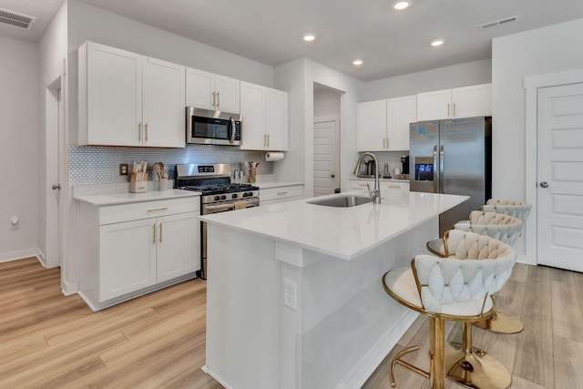 kitchen featuring visible vents, a breakfast bar area, stainless steel appliances, and a sink