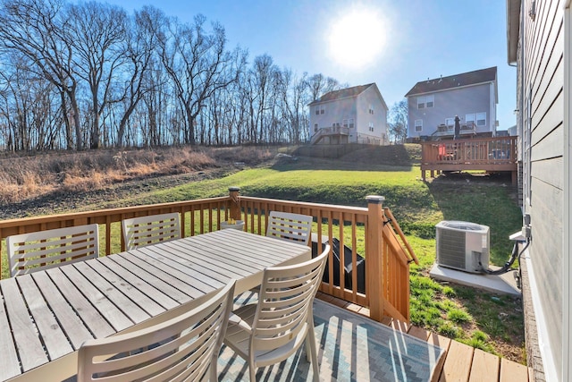 wooden terrace featuring central air condition unit, outdoor dining area, and a yard