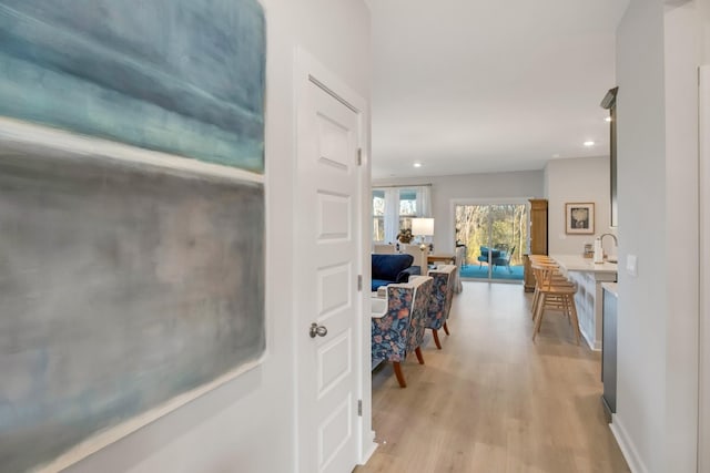 corridor with light wood finished floors, recessed lighting, and baseboards