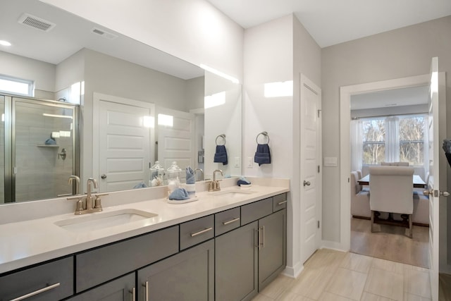 ensuite bathroom featuring double vanity, a stall shower, visible vents, and a sink