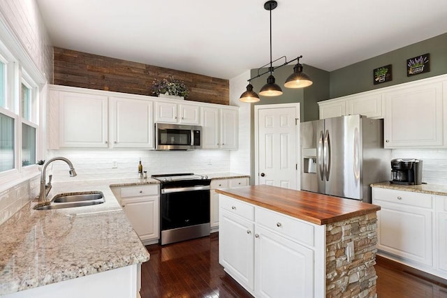 kitchen with backsplash, appliances with stainless steel finishes, white cabinets, wood counters, and a sink