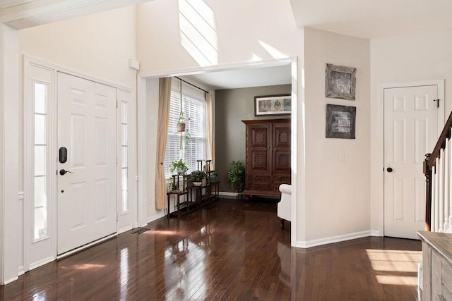 foyer featuring baseboards, hardwood / wood-style floors, and stairs