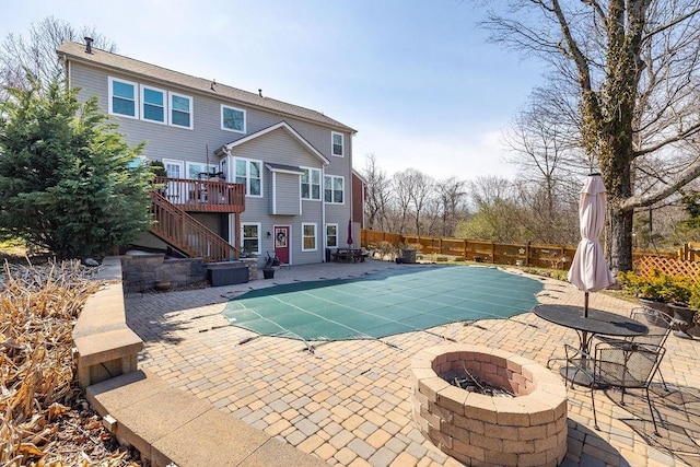 view of pool featuring a patio, fence, stairway, a fire pit, and a wooden deck