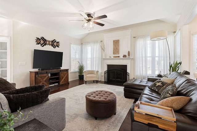 living area featuring baseboards, a fireplace with flush hearth, lofted ceiling, wood finished floors, and a ceiling fan