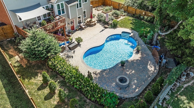 view of pool with a wooden deck, an outdoor fire pit, a fenced backyard, and a patio area