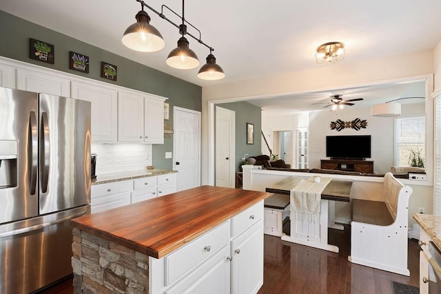 kitchen with white cabinets, a ceiling fan, stainless steel fridge, and butcher block counters