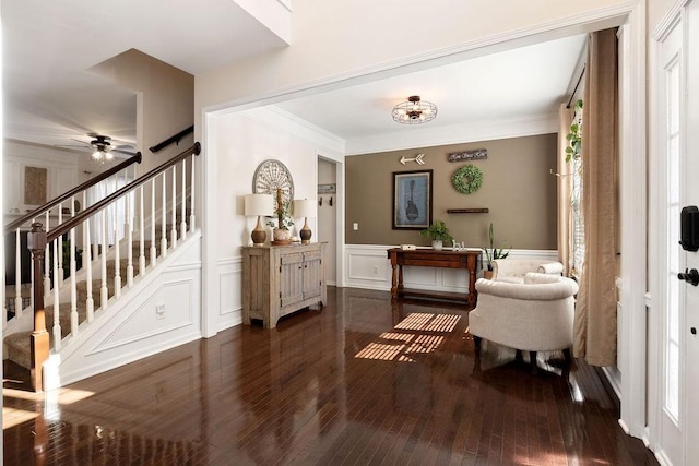 entryway featuring a wainscoted wall, ornamental molding, hardwood / wood-style floors, stairway, and a decorative wall