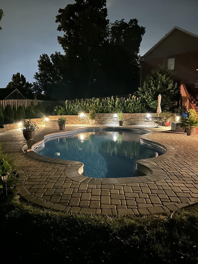 pool at twilight featuring an outdoor pool, a patio, and a fenced backyard