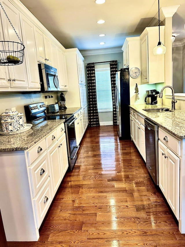 kitchen featuring wood finished floors, stainless steel appliances, crown molding, and a sink