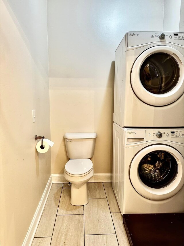 washroom featuring laundry area, stacked washer / drying machine, and baseboards