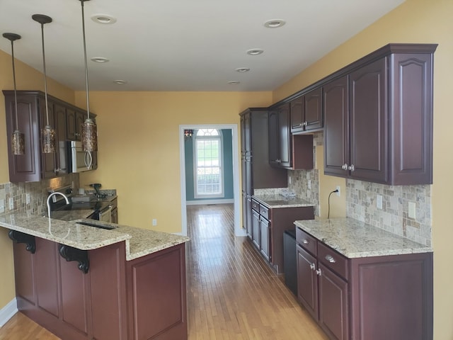 kitchen with light wood-type flooring, appliances with stainless steel finishes, a peninsula, baseboards, and light stone countertops