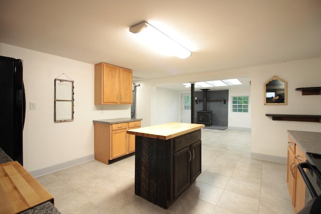 kitchen with wooden counters, freestanding refrigerator, baseboards, range, and a wood stove