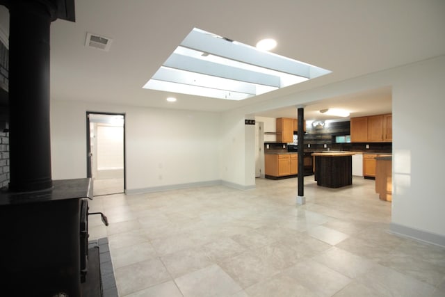 living area featuring visible vents, recessed lighting, a wood stove, and baseboards