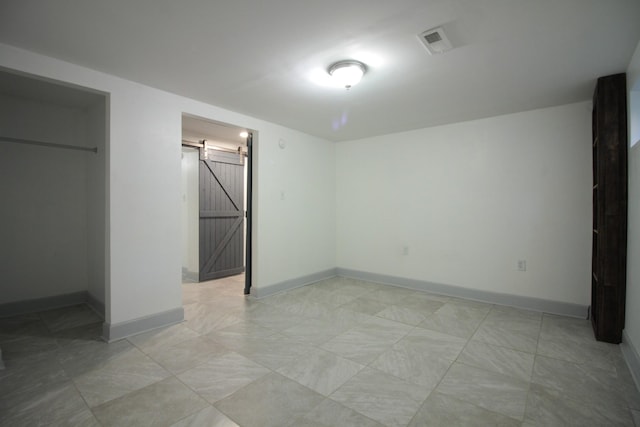 unfurnished bedroom with a barn door, baseboards, and visible vents