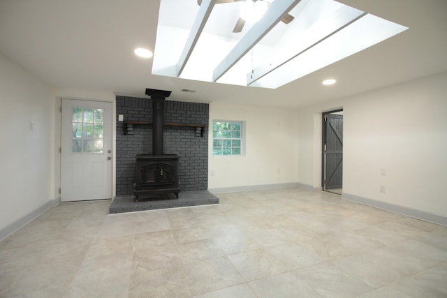 unfurnished living room with a wealth of natural light, a wood stove, and baseboards